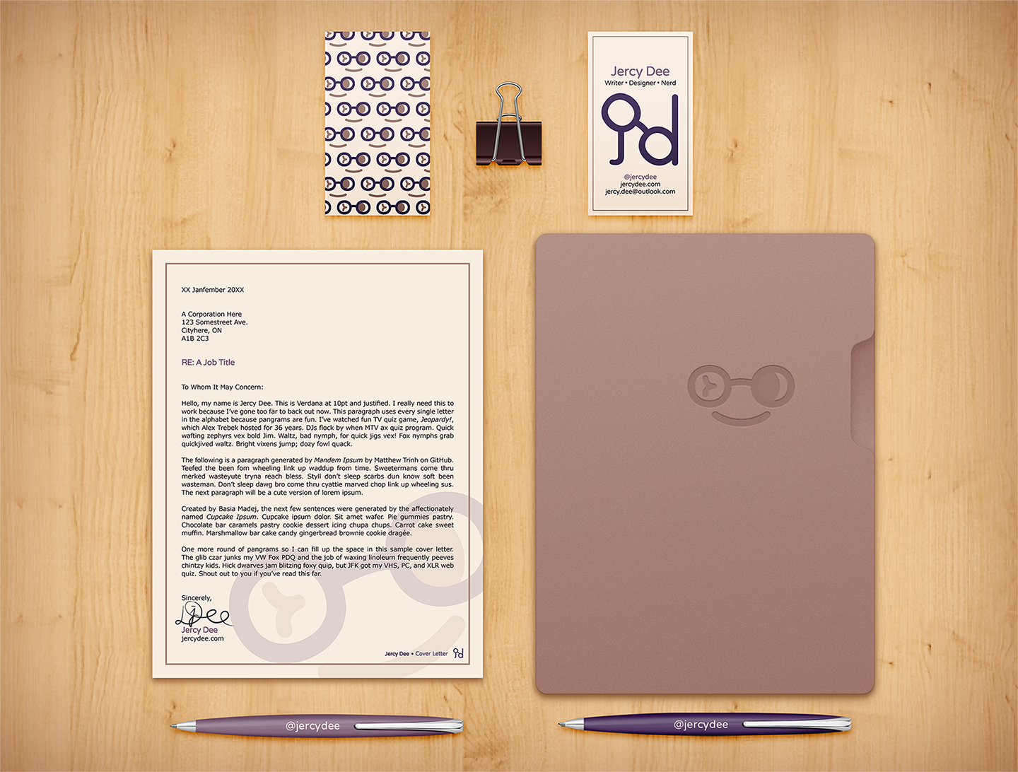 My brand applied onto different stationery/printed items (business cards, cover letter, folder, and pens) along with a dark purple bulldog clip against a wood background.